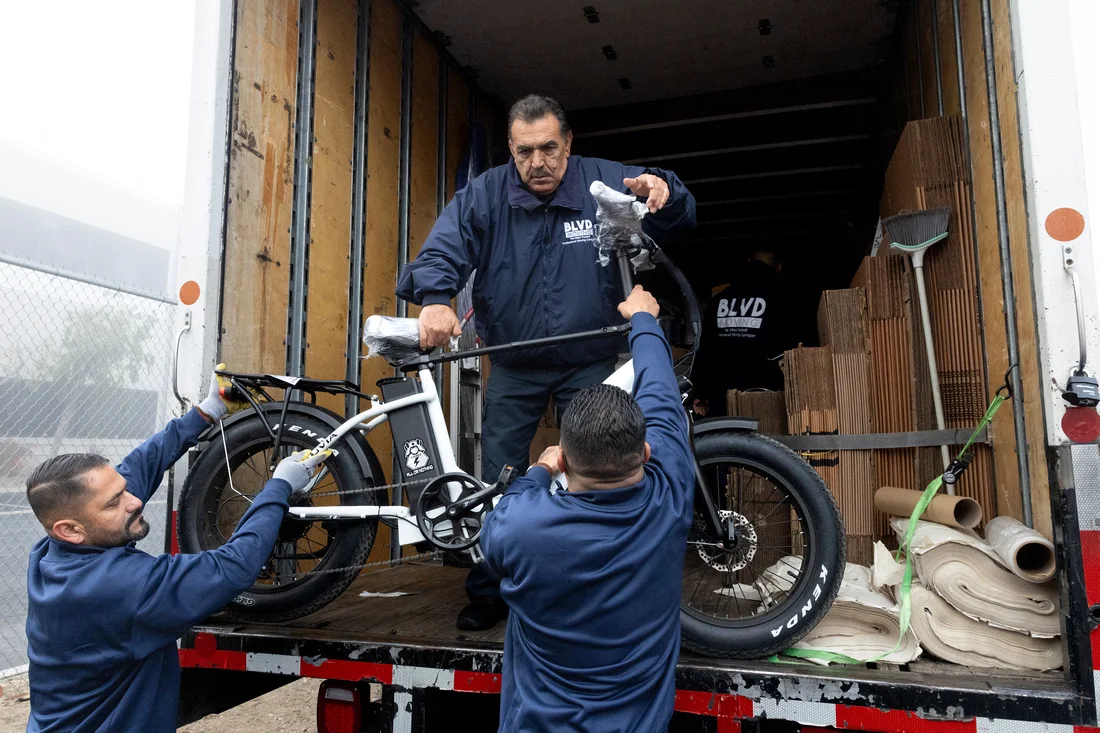 BLVD movers carefully loading a protected bicycle into the truck